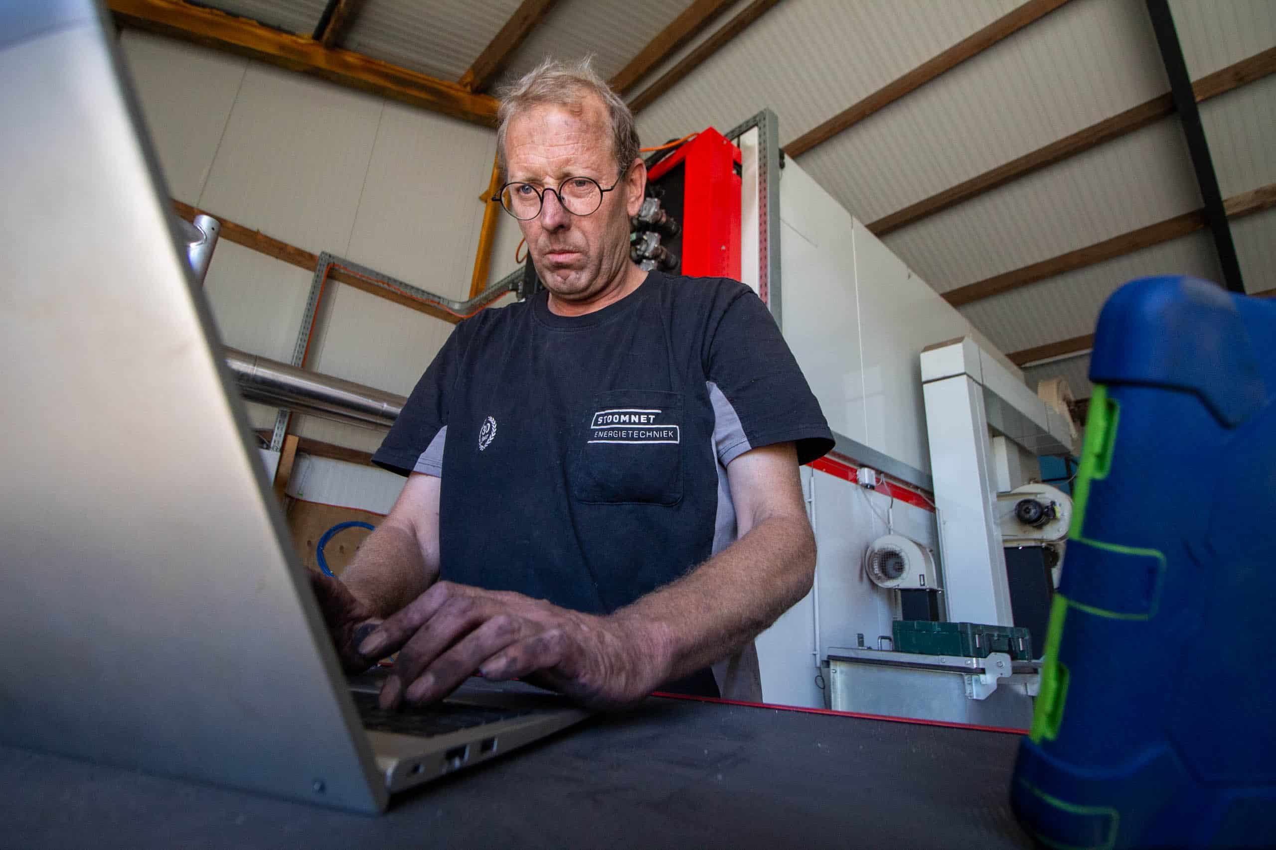 Stoomnet monteur aan het werk bij pelletkachelinstallatie in veeteeltsector.