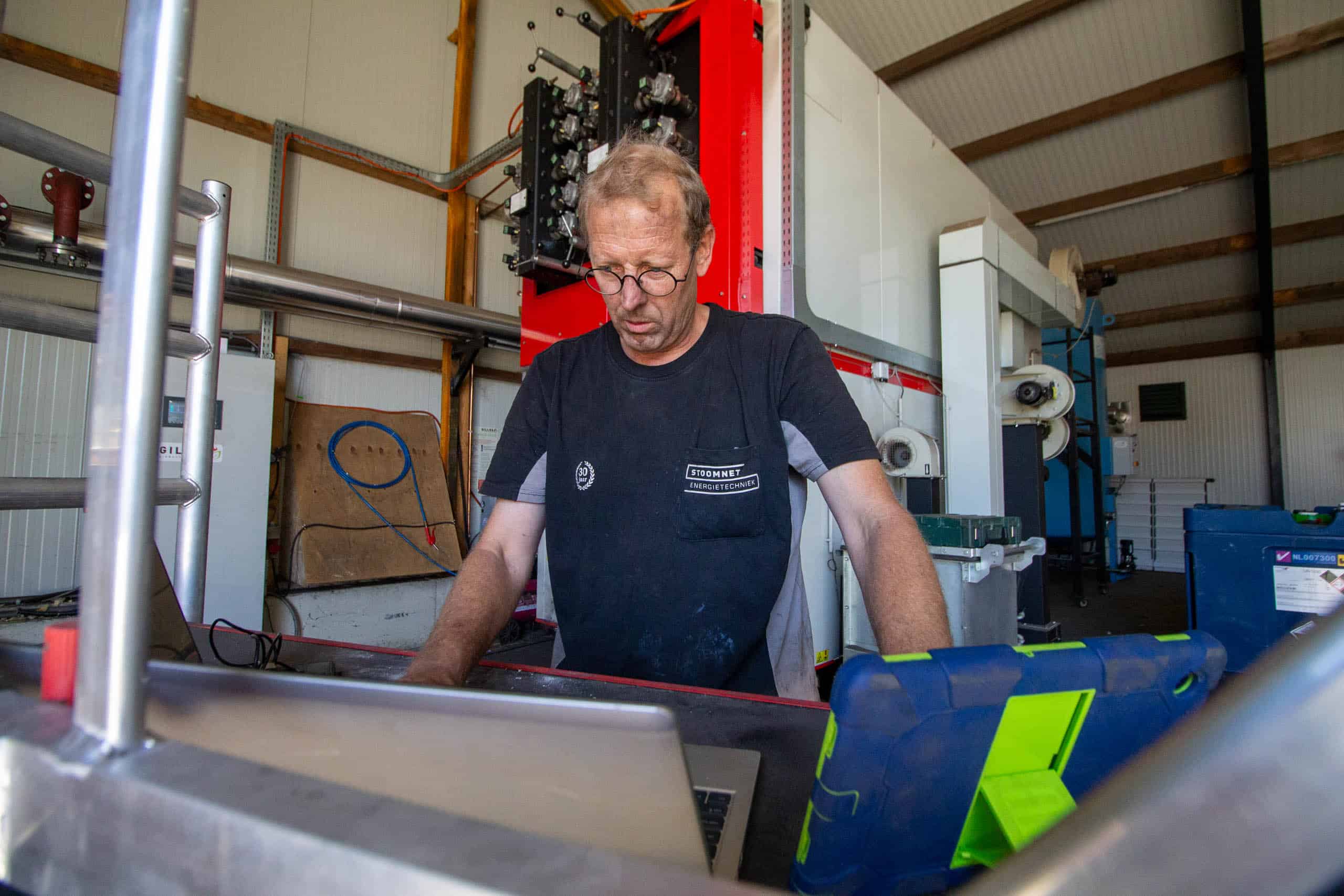 Stoomnet monteur voert werkzaamheden uit bij pelletkachelinstallatie in veeteeltsector