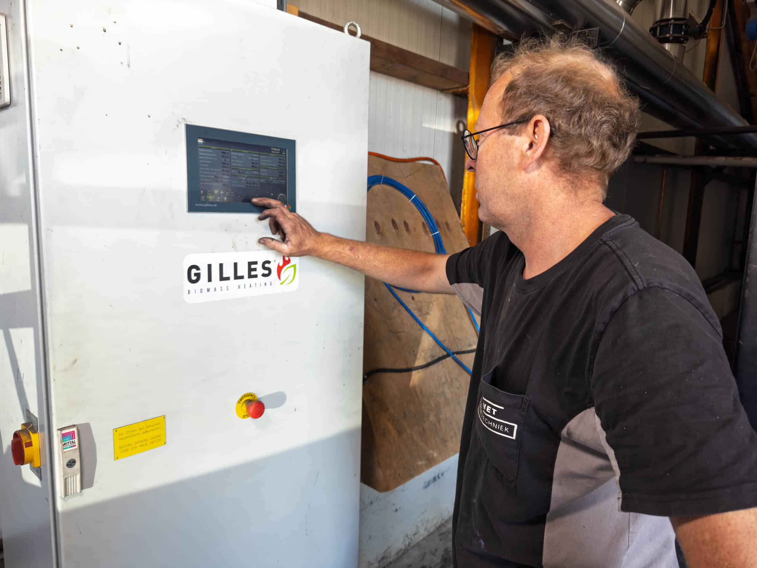 Stoomnet monteur aan het werk bij bedieningspaneel Gilles pelletkachelinstallatie.